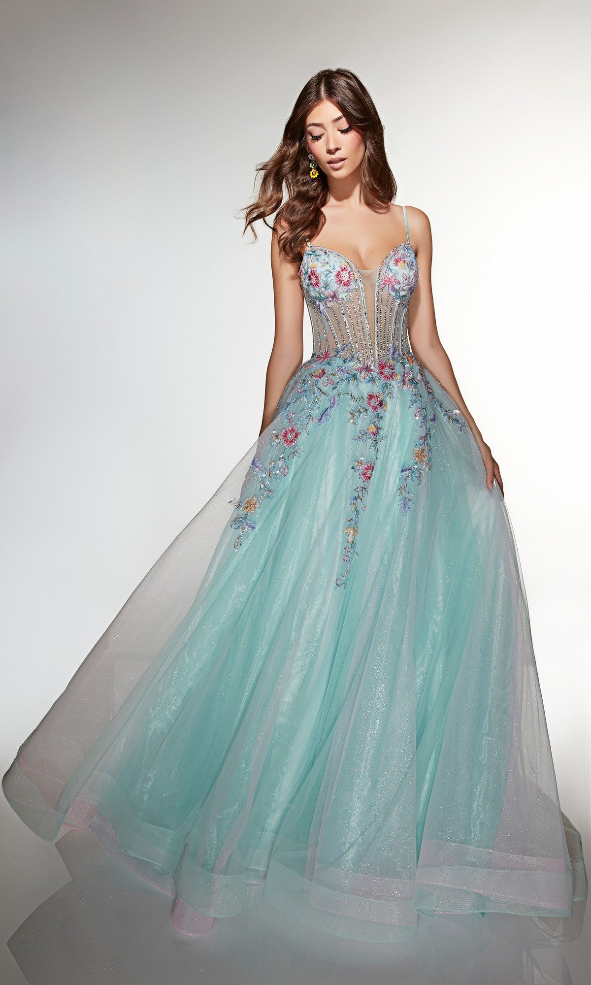 Woman wearing the Alyce 62068 Long Prom Dress, a light blue gown with a sleeveless floral corset bodice, sheer details, and thin straps, standing against a plain background.